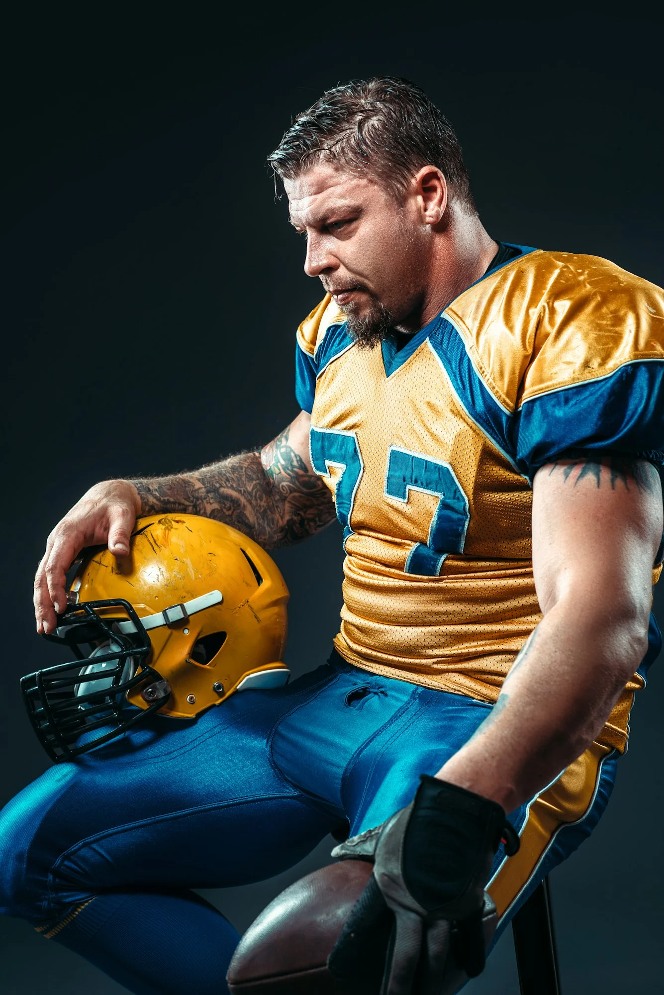 Football player with ball and helmet in hands